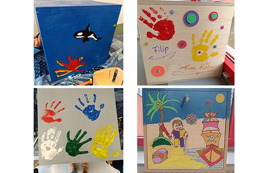 Kreativwerkstatt Rhein Akademie Das Bild zeigt eine Collage von vier Holzkisten, die von Kindern bemalt wurden. Die Motive umfassen Meerestiere, Handabdrücke und eine Strandszene mit einem Piratenschiff.